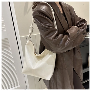 Detail of a creamy white PU leather hobo bag with silver ring and knot decoration