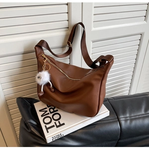 Détail du sac marron en cuir grainé avec fermeture dorée et pendentif peluche blanc