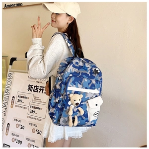 Close-up of blue camouflage nylon school backpack featuring cute bear plush keychain