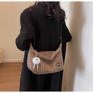 Detailed back view of a brown plaid crossbody bag with a white plush eye charm
