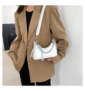 Sac croissant blanc avec chaîne argentée porté sur l'épaule d'un mannequin