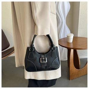 Detail of a vintage black hobo handbag with white stitching and silver buckle on model