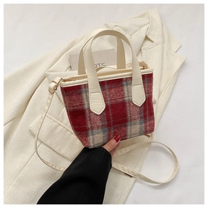 Close-up of red and grey plaid wool tote bag with cream leather handles and strap