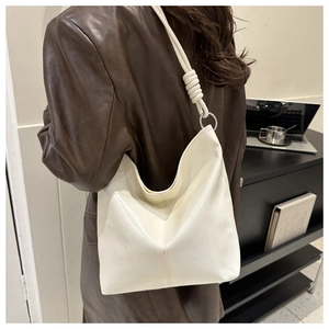 Detail of cream leather hobo bag with unique silver ring and knot shoulder strap