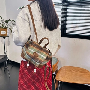 Close-up of vintage check wool backpack with leather flap and drawstring detail