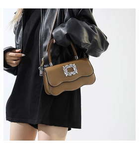 Détail de sac à main marron avec rabat festonné et boucle carrée en cristal étincelant