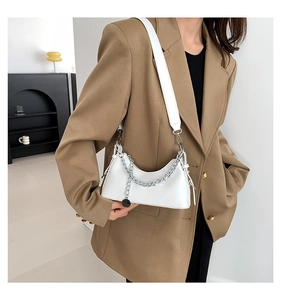 Sac sous le bras minimaliste en cuir blanc avec chaîne argentée porté par un mannequin