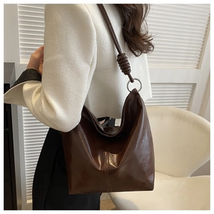 Detail view of the twisted knot shoulder strap and silver metal ring on the dark brown tote