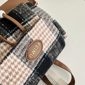 Close-up of houndstooth wool fabric texture on handbag with brown leather logo detail