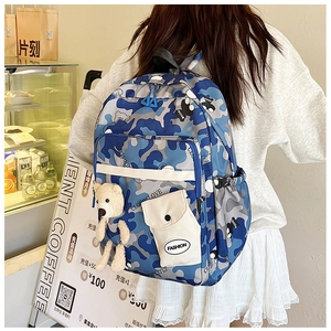 Detail view of camouflage nylon student backpack with bear pendant and fashion tag
