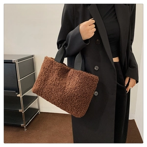 Detail of deep brown faux shearling tote bag featuring soft teddy texture and black strap