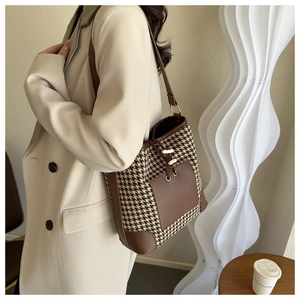 Detail of retro houndstooth bucket bag with brown leather trim and drawstring closure