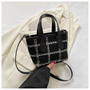 Detail of tweed tote bag showing woven plaid texture and leather shoulder strap