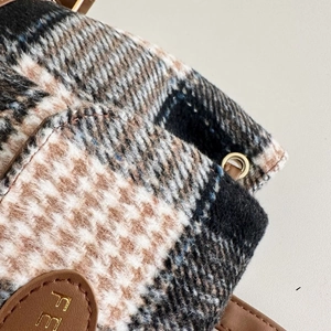 Macro shot of plaid wool fabric texture with leather trim and golden metal ring hardware