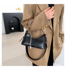 Détail du sac sous l'aisselle en cuir noir avec chaîne argentée et large bandoulière