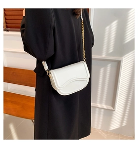 Close-up of a white minimalist saddle bag with chain strap worn as a shoulder bag