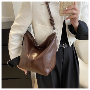 Close-up of brown tote bag featuring unique knot detail and silver metal ring hardware