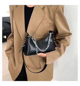 Détail du sac sous le bras en forme de croissant noir avec chaîne décorative en métal argenté