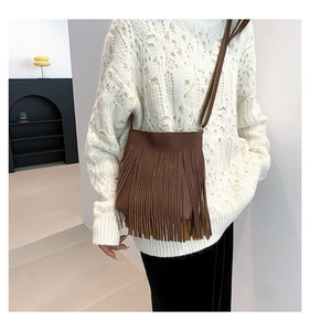 Detailed close-up of brown fringe crossbody bag showing textured lychee leather and tassels