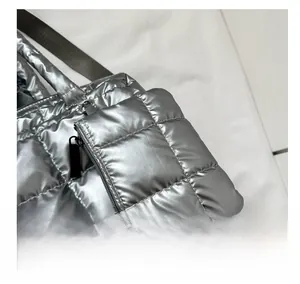 Close-up of silver quilted tote bag featuring a matching mini coin purse attachment