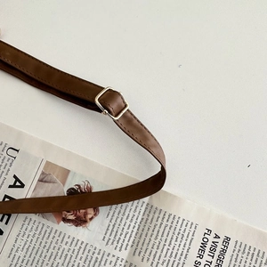 Detailed close-up of dark brown leather strap with silver adjustable metal buckle on a desk
