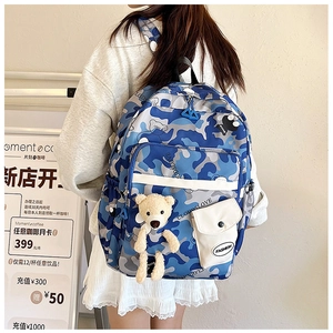 Detail view of blue camo backpack with a cute teddy bear charm and fashion label