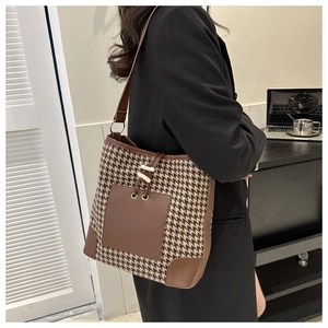 Detail of vintage houndstooth tote bag with brown leather accents shown on a model