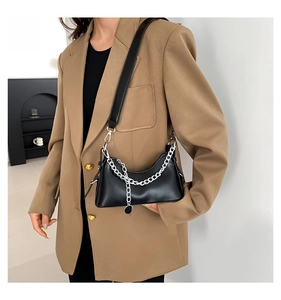 Détail du sac croissant noir avec chaîne en métal argenté et finition mate texturée