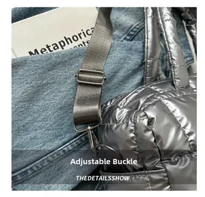 Detail of adjustable nylon strap and metal buckle on a silver quilted puffer tote bag
