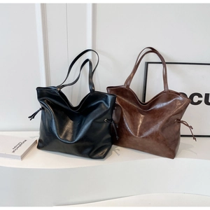 Detail view of large matte PU leather tote bags in black and dark brown colors