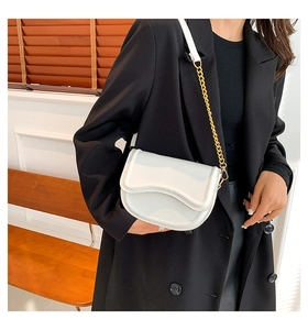 Close-up of white saddle bag featuring a smooth glossy finish and golden metal chain strap