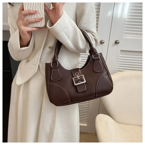 Detailed macro view of dark brown PU leather handbag with white stitching and silver buckle