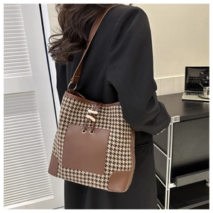 Chic houndstooth bucket bag with brown leather trim shown on shoulder for daily commute
