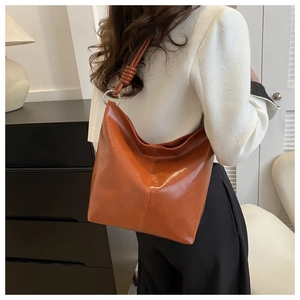 Macro detail of glossy brown-orange tote bag with stylish knot strap and silver ring buckle