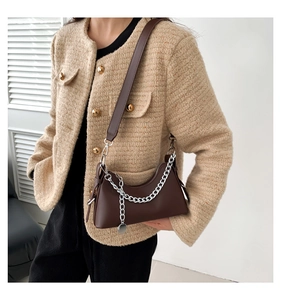 Sac sous le bras marron avec chaîne argentée porté par un mannequin en manteau beige
