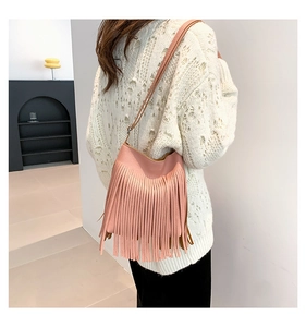 Side view of a pink fringe crossbody bag with litchi texture on a female model