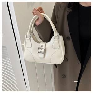 Detail view of cream white leather handbag with metal buckle and integrated handle