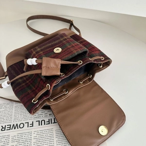 Detailed close-up showing the plaid wool texture and leather drawstring of the retro backpack