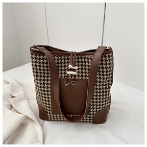Detail of houndstooth fabric and brown leather pocket on a large tote shoulder bag