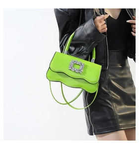 Détail du sac vert néon à bords ondulés avec une boucle florale en cristal brillant