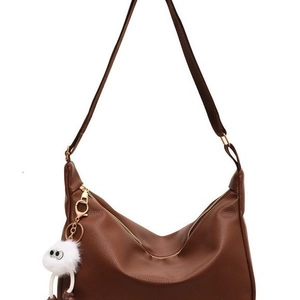 Sac bandoulière en cuir marron à texture litchi avec un joli pompon blanc en peluche