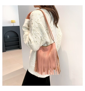 Detail of pink tassel crossbody bag showing long fringes and sleek leather texture