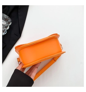 Detailed side view of a bright orange crossbody bag with smooth faux leather finish