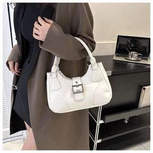 Detail of a white faux leather hobo bag with silver buckle worn by a model