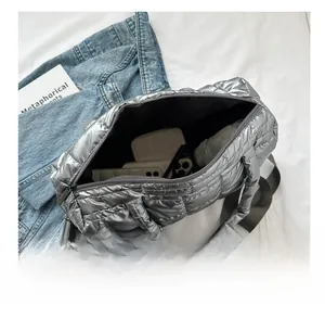 Top-down view of spacious interior of silver puffer tote bag showing phone and sunglasses