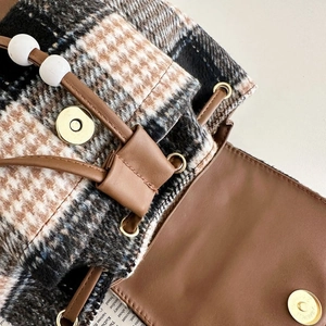 Detail view of houndstooth wool fabric bag with brown leather drawstring and gold magnetic clasp
