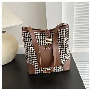 Detail of houndstooth tote bag with brown leather trim and horn shaped buckle decor