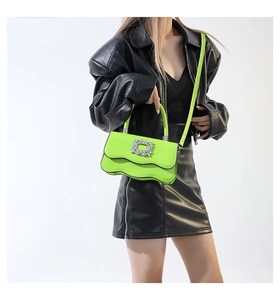Détail du sac vert citron avec base ondulée et boucle luxueuse sertie de cristaux brillants