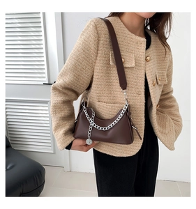 Sac hobo marron foncé avec chaîne argentée porté par un mannequin en veste tweed
