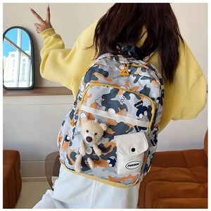 Detailed back view of camo school backpack with plush bear charm on yellow hoodie model